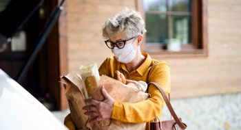 senior-woman-with-face-mask-outdoors-with-shopping-P4BEJZG.jpg